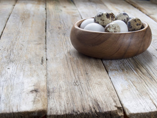 Fototapeta na wymiar Quail and chicken eggs in wooden bowl, easter background