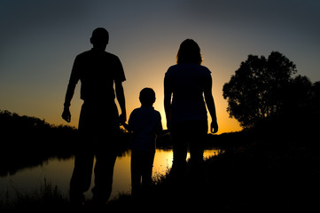 Mother, father and  kid silhouettes at sunset