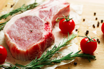 Pieces of crude meat with rosemary and tomatoes.