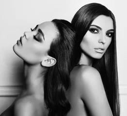 Modestudiofoto von zwei schönen jungen Frauen mit dunklen Haaren, die zusammen posieren © Slava_Vladzimirska