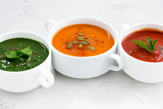 assortment of colorful vegetable cream soup on a white table