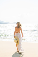 Fototapeta na wymiar Classy woman holding a straw hat at the beach Vacation Holiday C