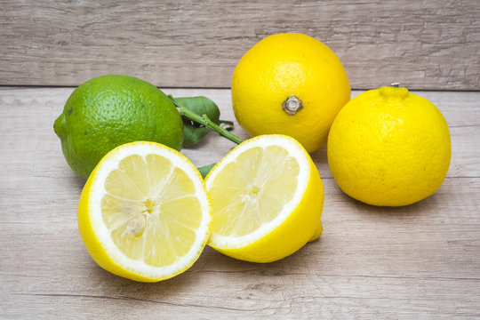 several mature citrus on an old wooden table - lemon and lime
