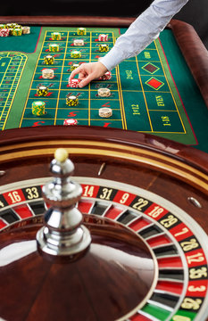 Roulette and piles of gambling chips on a green table. 