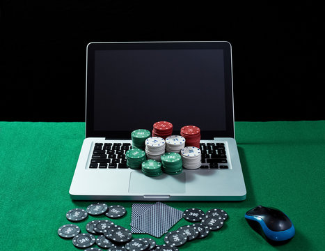 Casino chips and cards on keyboard notebook at green table. 