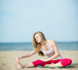 Young lady practicing yoga. Workout near ocean sea coast.