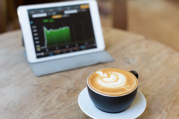 hot latte art coffee in black mug  with tablet background
