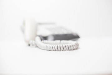 Fototapeta na wymiar White digital phone with handset and cord on white table