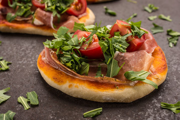 Kleine Pizza mit Schinken, Tomate und Rauke