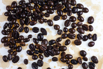 Coffee beans and coffee stains on a white tablecloth..