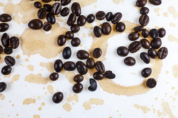 Coffee beans and coffee stains on a white tablecloth..