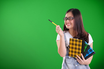 Funny school girl pointing at copy space on green chalkboard