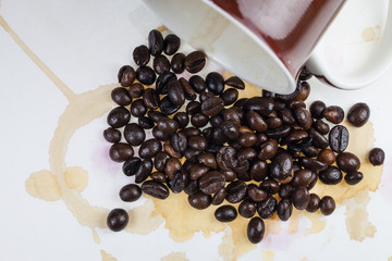 Coffee beans and coffee stains on a white tablecloth..
