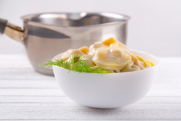 Dish with cooked dumplings with butter and dill on background scoop