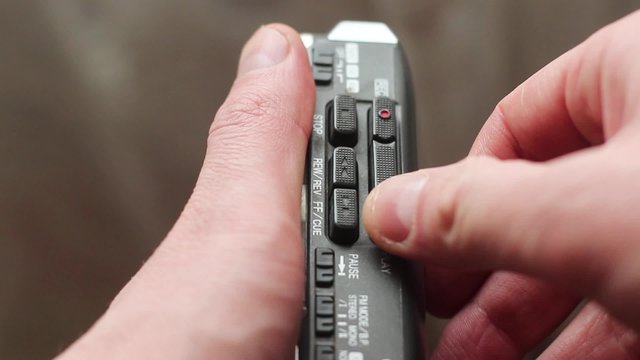 The man inserts a cassette into the old player and presses play.