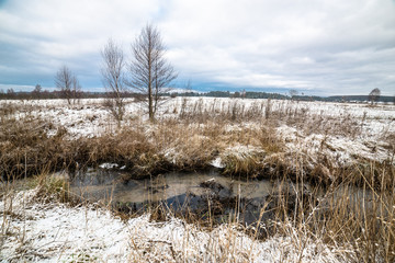 Landscape of fields by the river during thaws at early spring
