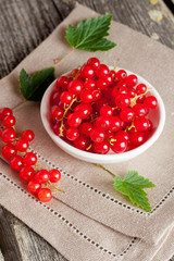 bowl of red currant on wooden background, vertical close-up