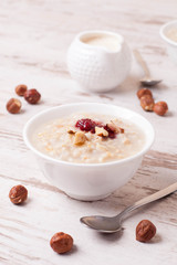 Oatmeal with milk, nuts and strawberry jam and milk jug
