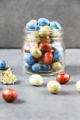 Chocolate eggs in the jar, colorful, gray background.