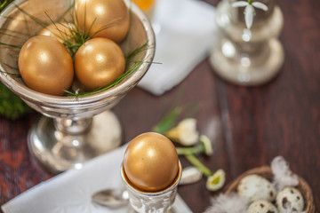 eine silberne Schale mit goldenen Eiern auf dunklem Holztisch von oben