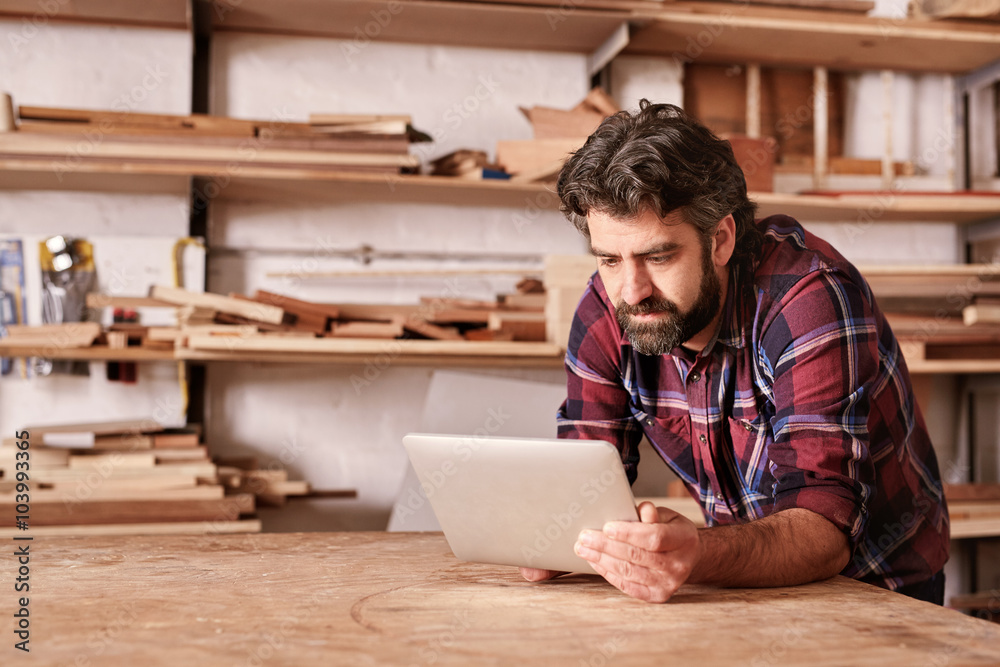 Sticker Woodwork craftsman in his studio using a digital tablet