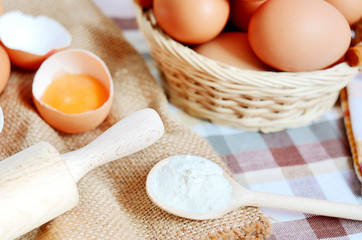 Wicker basket with eggs and raw egg on a linen tablecloth