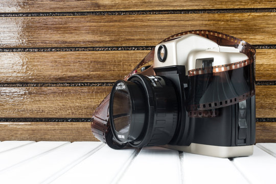 Vintage photo camera on white wooden base and brown wooden background 