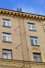 Пожарная лестница на стене кирпичного дома советской постройки