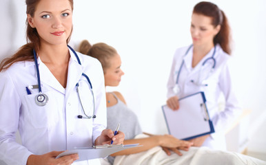 Fototapeta premium Smiling female doctor with a folder in uniform standing at hospital