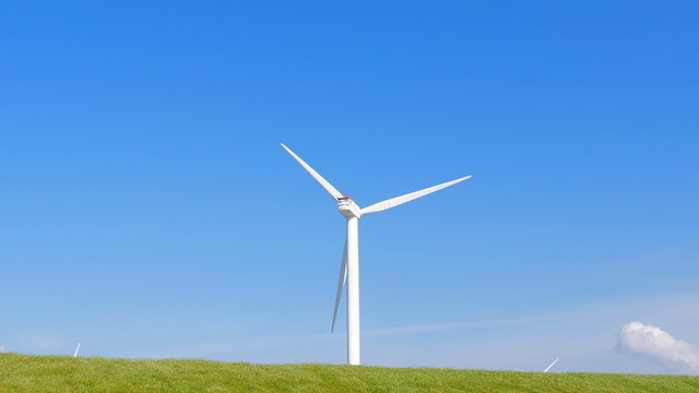 Wind turbine in green field with small clouds in spring

