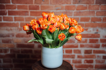 bouquet of orange tulips near brick wall