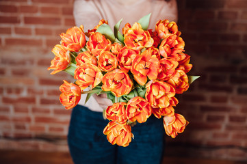 bouquet of orange tulips near brick wall