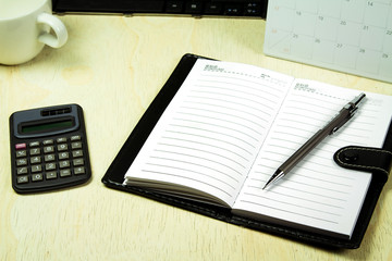 notebook pen calculator calendar on wood table