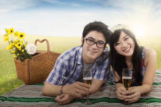 Cheerful couple with champagne in nature