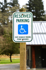 metal sign on wooden post stating reserved parking for handicap people