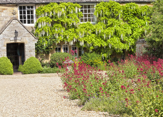 Traditional English cottage courtyard with gravel driveway, stone mushroom, colourful garden...