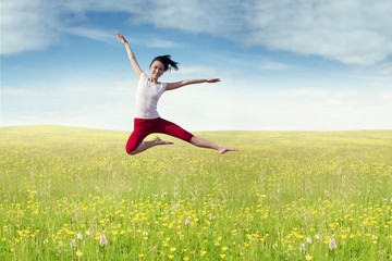 Joyful woman leaps at field in springtime