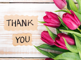 "Thank you" card and tulip bouquet on white wooden background