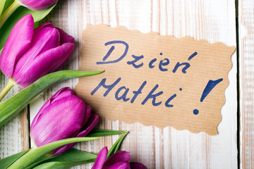 Mother's Day card and a bouquet of beautiful tulips on wooden background, with Polish words "Mother's Day"
