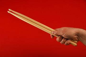 Man hand with drumsticks and devil horns over red
