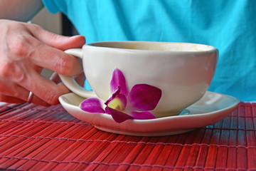 Woman hand holding coffee cup with flower