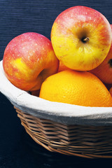Basket with apples and oranges on a blue background