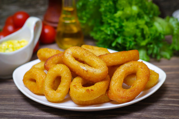 deep fried calamari with sauce and salad on a wooden background