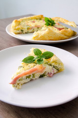 Homemade Spinach and Bacon Egg Quiche in a pie crust cut piece on plate. French cuisine