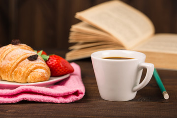 cup of coffee and a croissant and book