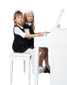 Two girls of preschool age diligently play the piano - Isolated on white background