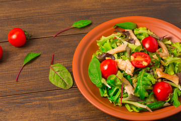 Fresh salad with chicken breast, arugula and tomato.