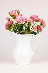 Fototapeta premium Pink flowers in white jug. Roses in jug.