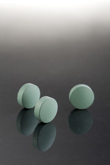 Green medicine pills. Pharmaceutical medicament. Antibiotic, painkiller or narcotic, closeup.