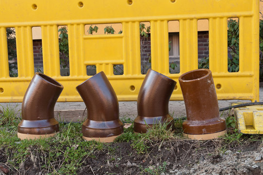 Rohrb&ouml;gen aus Ton stehen vor einer gelben Absperrbake